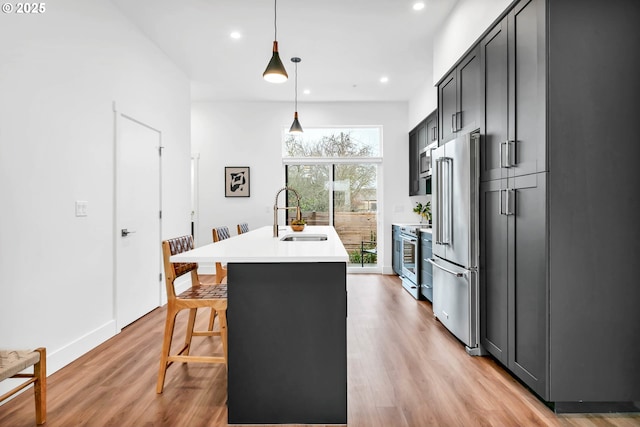 kitchen with sink, stainless steel appliances, pendant lighting, a kitchen bar, and a center island with sink