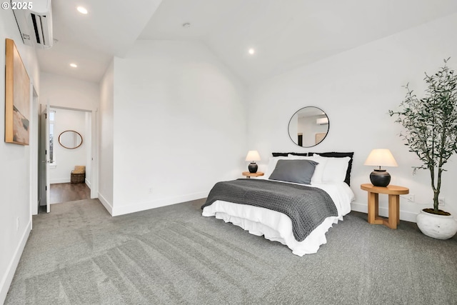 bedroom featuring lofted ceiling, carpet floors, a wall unit AC, and connected bathroom