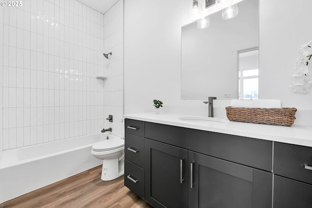 full bathroom featuring hardwood / wood-style floors, tiled shower / bath combo, toilet, and vanity