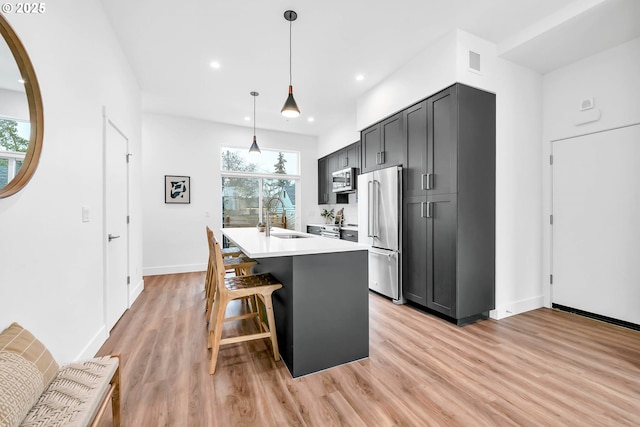 kitchen with appliances with stainless steel finishes, a breakfast bar, sink, pendant lighting, and a center island with sink