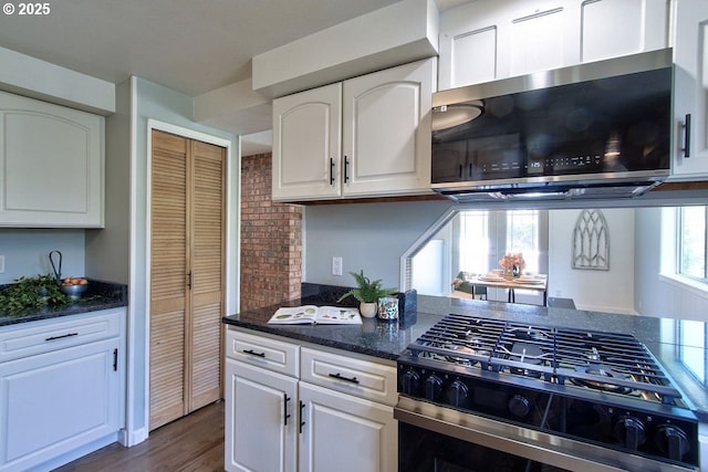 kitchen featuring white cabinets, stainless steel appliances, dark wood-style floors, and dark stone countertops