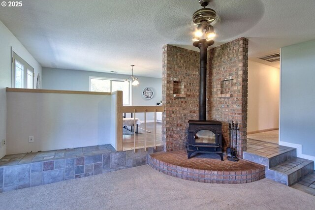 living room featuring a ceiling fan, visible vents, carpet, and a wood stove
