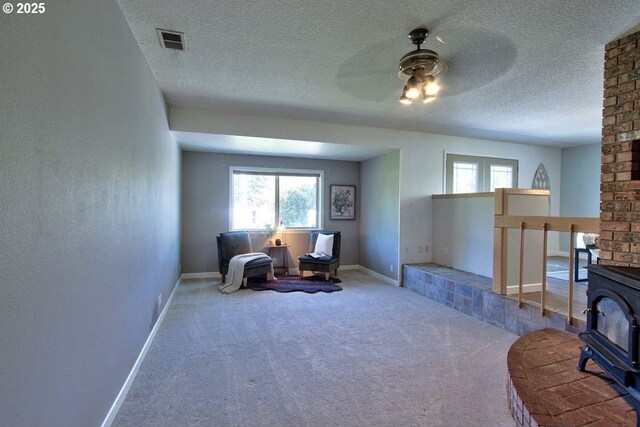sitting room featuring a ceiling fan, a textured ceiling, visible vents, carpet floors, and baseboards