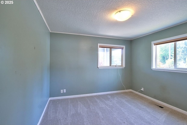 spare room with a textured ceiling, visible vents, crown molding, baseboards, and carpet