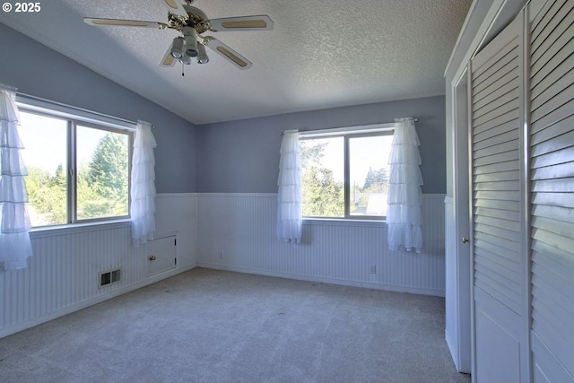 unfurnished bedroom featuring visible vents, a textured ceiling, wainscoting, and carpet flooring