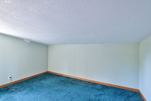 carpeted spare room featuring a textured ceiling and baseboards