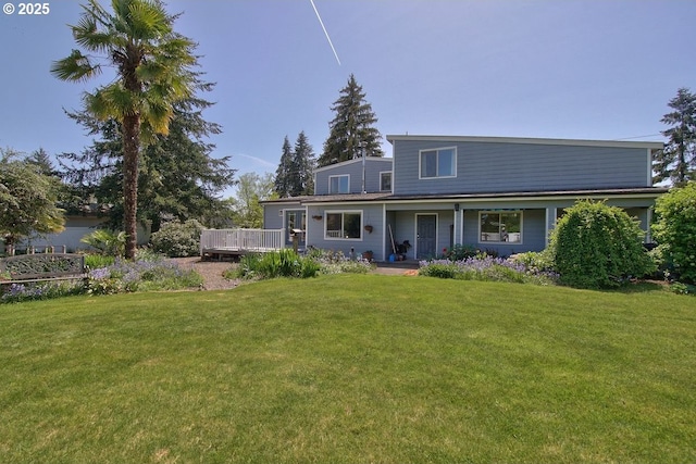 rear view of house featuring a lawn and a deck