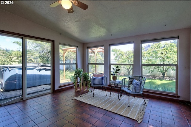 sunroom with tile patterned flooring, ceiling fan, vaulted ceiling, and a textured ceiling