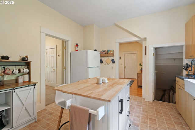 11151117 N Beech St, Portland, OR 97227 - kitchen with freestanding refrigerator, wood counters, a center island, and a kitchen bar