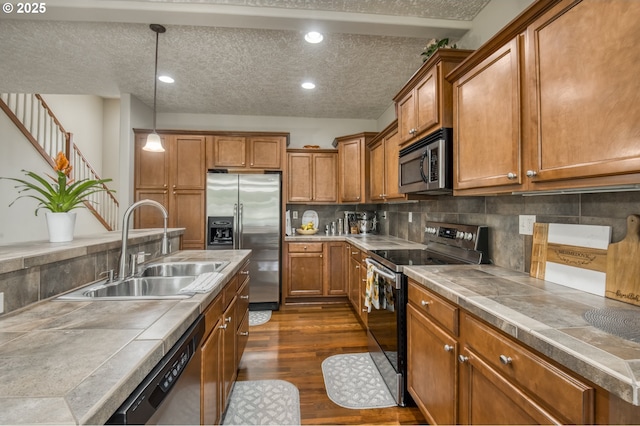 2459 SW Sandlewood Ln, Gresham, OR 97080 - kitchen with stainless steel appliances, brown cabinetry, dark wood-style flooring, backsplash, and recessed lighting