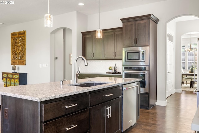 11473 NW W Rd, Portland, OR 97229 - kitchen with appliances with stainless steel finishes, dark wood finished floors, arched walkways, dark brown cabinets, and recessed lighting