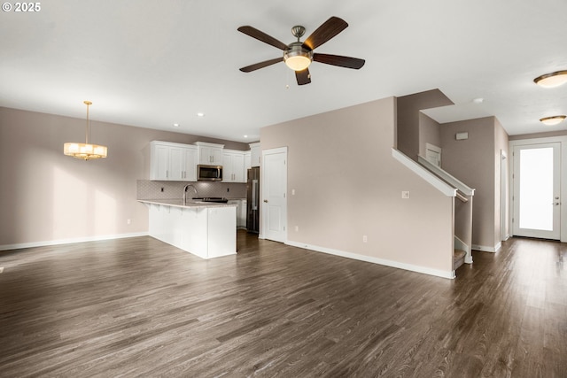 unfurnished living room featuring dark wood-style floors, ceiling fan, stairway, and baseboards