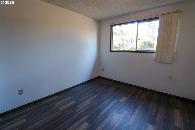 spare room featuring dark hardwood / wood-style flooring and a textured ceiling