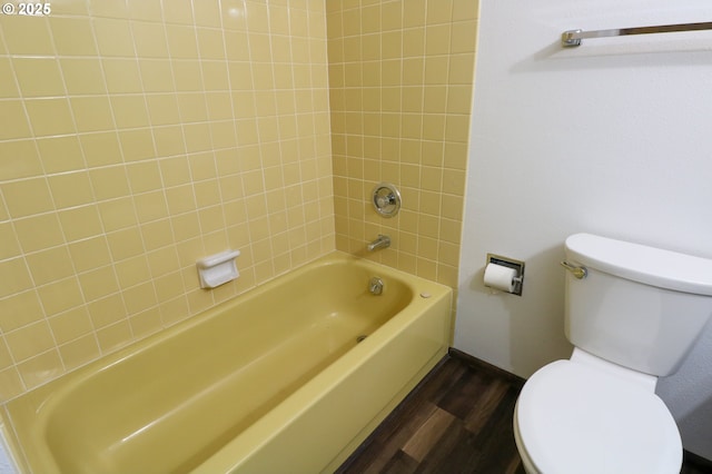 bathroom with toilet, tiled shower / bath, and wood-type flooring