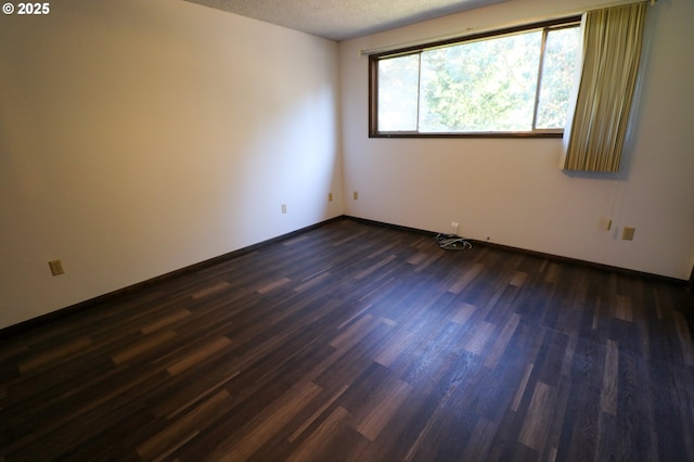 unfurnished room featuring dark wood-type flooring and a textured ceiling