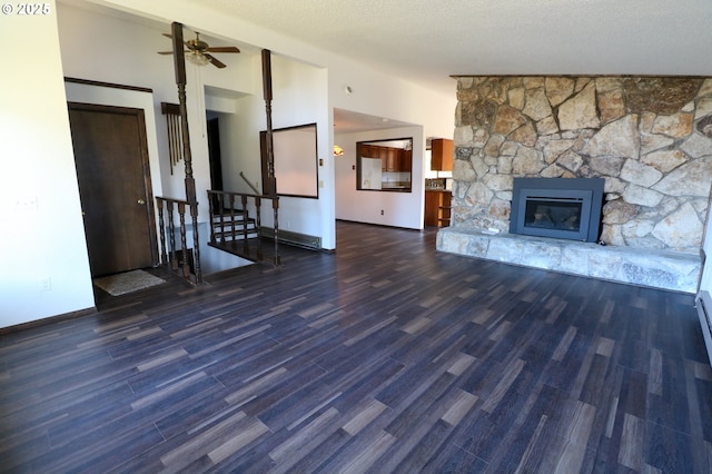 unfurnished living room featuring lofted ceiling, dark wood-type flooring, ceiling fan, and a stone fireplace