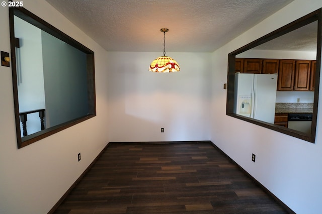 unfurnished dining area featuring a textured ceiling and dark hardwood / wood-style flooring