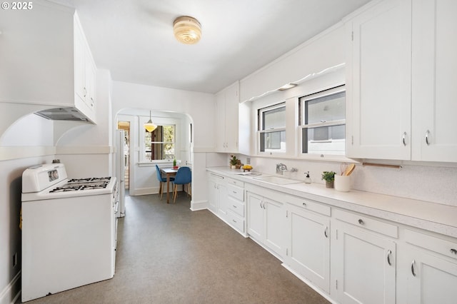 kitchen featuring arched walkways, a sink, white cabinetry, white appliances, and light countertops