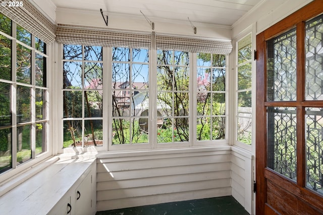 unfurnished sunroom featuring plenty of natural light and ornamental molding