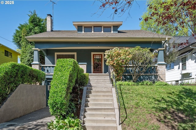 bungalow with a front lawn, a chimney, covered porch, and stairs
