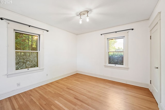unfurnished bedroom featuring light wood finished floors, baseboards, and multiple windows