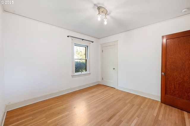 empty room featuring baseboards and light wood-type flooring