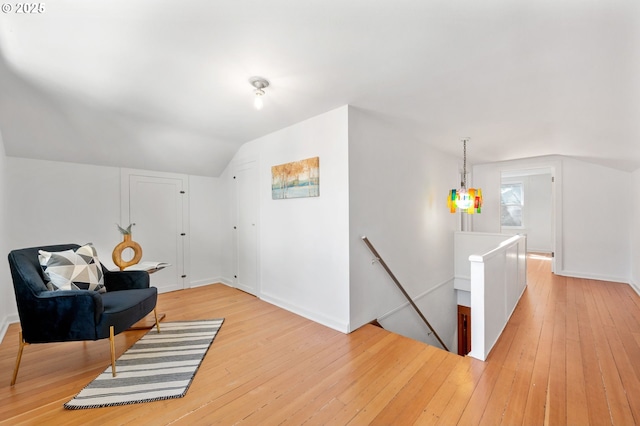 sitting room with lofted ceiling, an upstairs landing, light wood finished floors, and baseboards