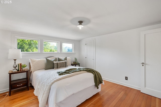 bedroom with light wood-type flooring, baseboards, and multiple windows