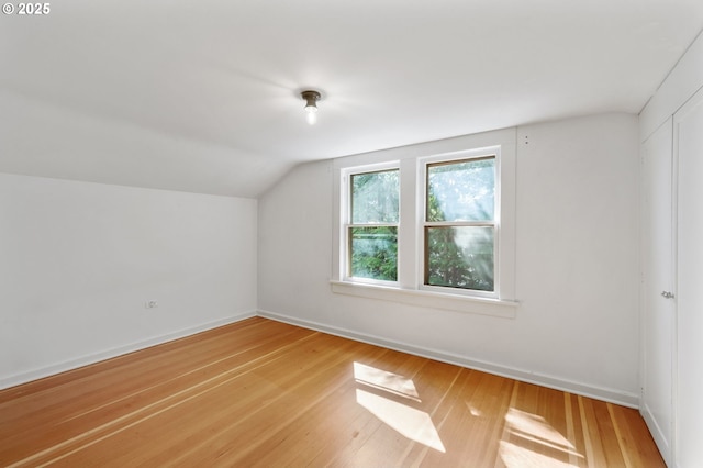 additional living space featuring light wood-type flooring, vaulted ceiling, and baseboards