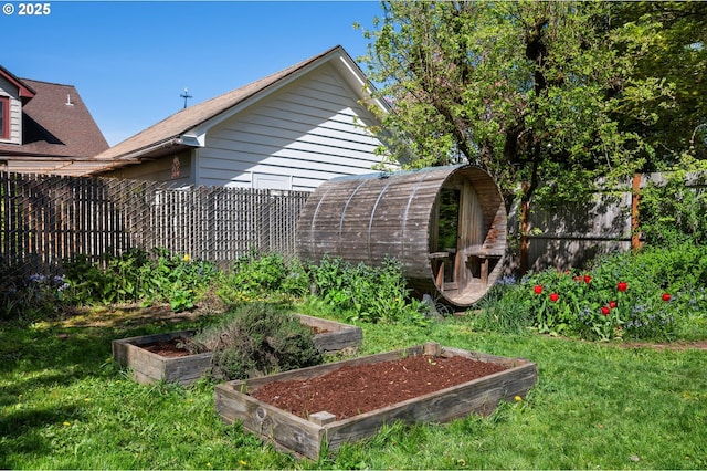 view of yard featuring fence private yard, an outdoor structure, and a garden
