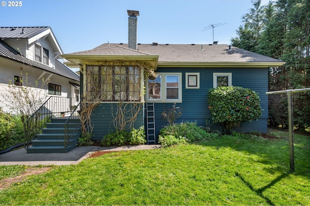 rear view of house featuring stairs, a lawn, a shingled roof, and a chimney