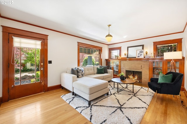 living area featuring a brick fireplace, wood finished floors, a wealth of natural light, and crown molding