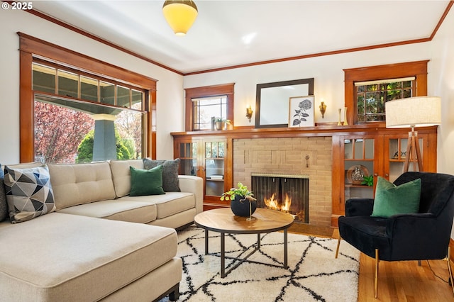 living area with crown molding, a brick fireplace, and wood finished floors