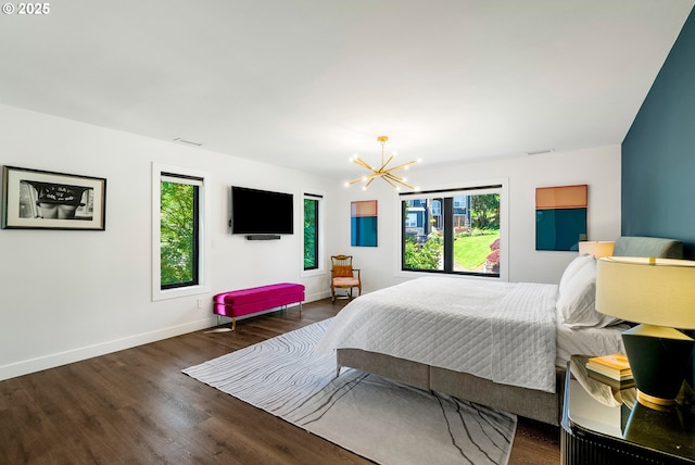 bedroom featuring an inviting chandelier, baseboards, wood finished floors, and visible vents