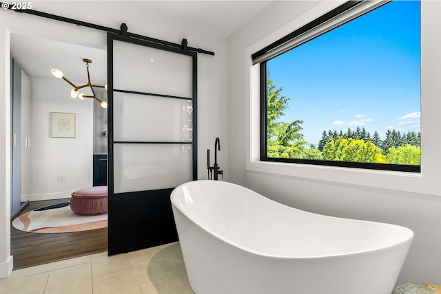 bathroom featuring a freestanding bath, tile patterned floors, and baseboards