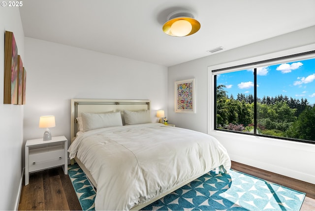 bedroom with baseboards, visible vents, and wood finished floors