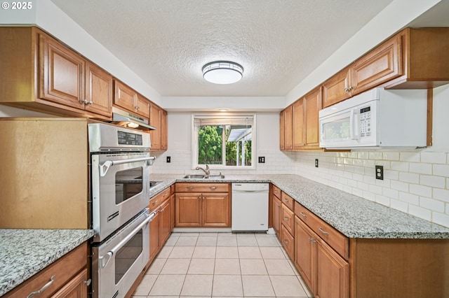 1631 N Clark St, Cornelius, OR 97113 - kitchen with white appliances, brown cabinetry, a textured ceiling, tasteful backsplash, and light stone countertops