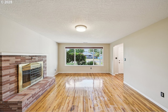 1631 N Clark St, Cornelius, OR 97113 - unfurnished living room featuring light wood-style floors, a brick fireplace, and a textured ceiling