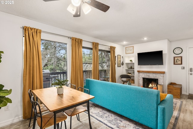 7538 SW Barnes Rd Unit H, Portland, OR 97225 - living area featuring wood finished floors, ceiling fan, a textured ceiling, baseboards, and a lit fireplace