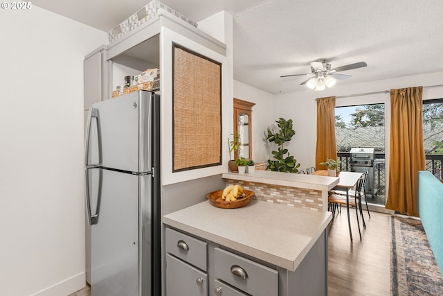 7538 SW Barnes Rd Unit H, Portland, OR 97225 - kitchen featuring freestanding refrigerator, gray cabinets, ceiling fan, a peninsula, and light countertops