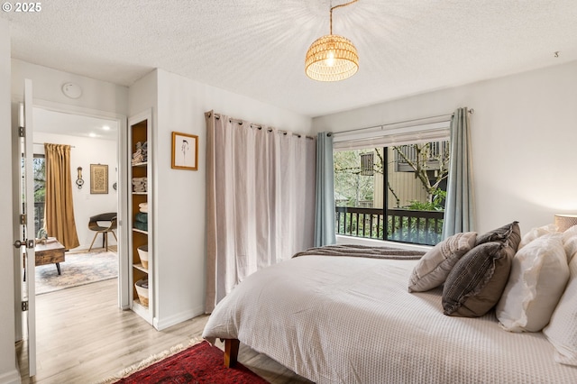 7538 SW Barnes Rd Unit H, Portland, OR 97225 - bedroom featuring light wood-type flooring, a chandelier, a textured ceiling, and baseboards