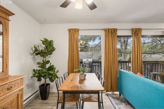 7538 SW Barnes Rd Unit H, Portland, OR 97225 - dining space featuring a baseboard radiator, wood finished floors, a ceiling fan, a textured ceiling, and baseboards
