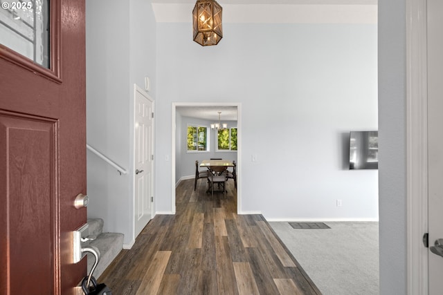 foyer entrance featuring visible vents, dark wood finished floors, baseboards, a chandelier, and stairs