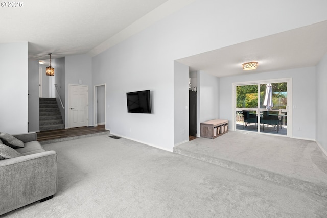 living room featuring visible vents, baseboards, carpet floors, lofted ceiling, and stairs