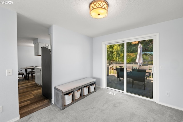 carpeted empty room with visible vents, baseboards, and a textured ceiling