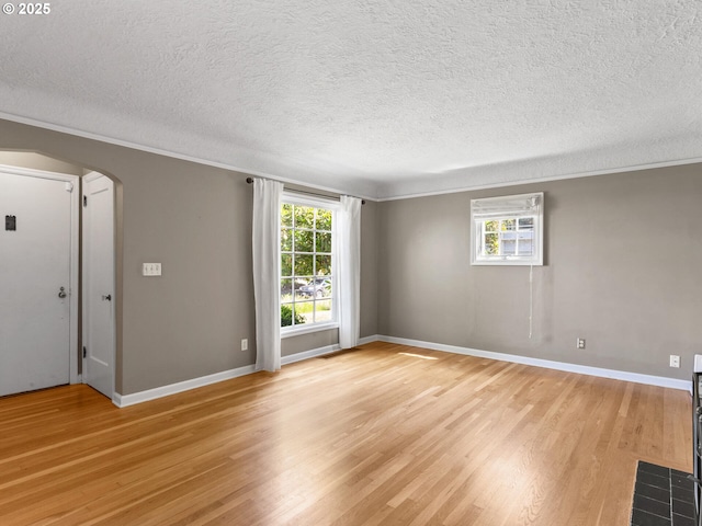 4561 NE 35th Ave, Portland, OR 97211 - empty room with arched walkways, light wood finished floors, crown molding, and a textured ceiling
