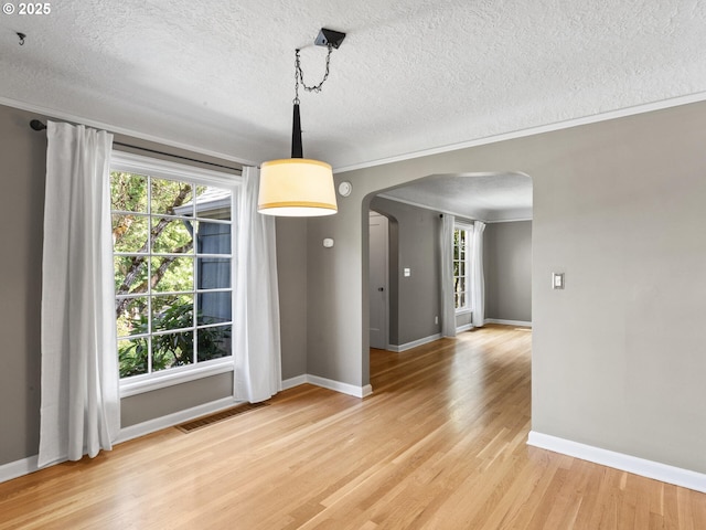 4561 NE 35th Ave, Portland, OR 97211 - unfurnished dining area featuring arched walkways, a textured ceiling, light wood finished floors, and ornamental molding