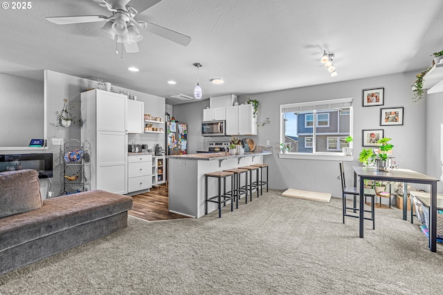 kitchen featuring stone counters, a kitchen bar, white cabinets, dark carpet, and appliances with stainless steel finishes