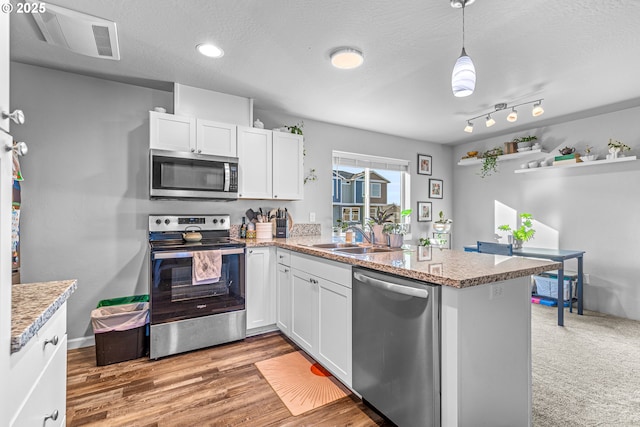 kitchen with kitchen peninsula, white cabinetry, sink, and stainless steel appliances