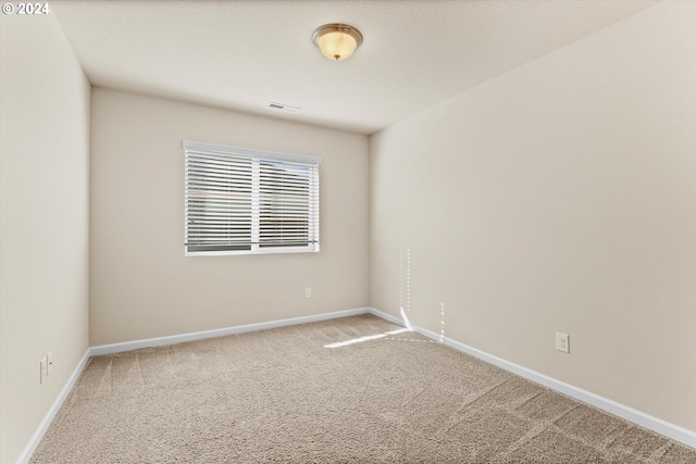 spare room featuring carpet flooring, baseboards, and visible vents